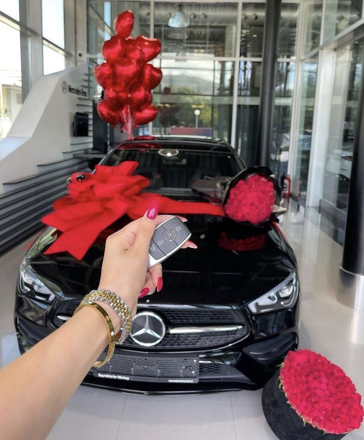 a woman holding a cell phone in front of a car with red flowers on it