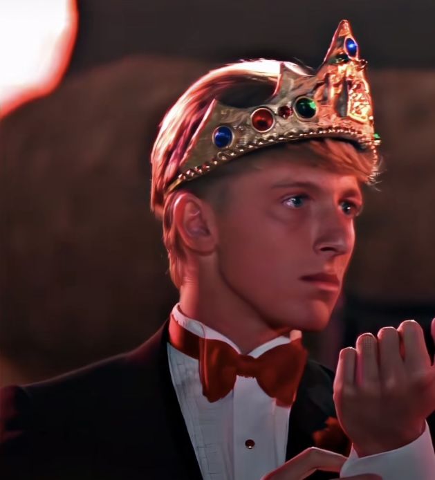 a young man wearing a crown and holding his hands together