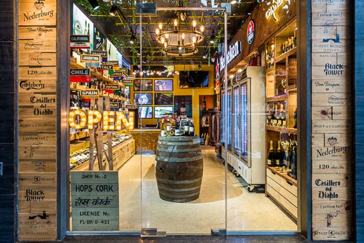 the inside of a liquor store with an open sign on the door and large wooden barrel