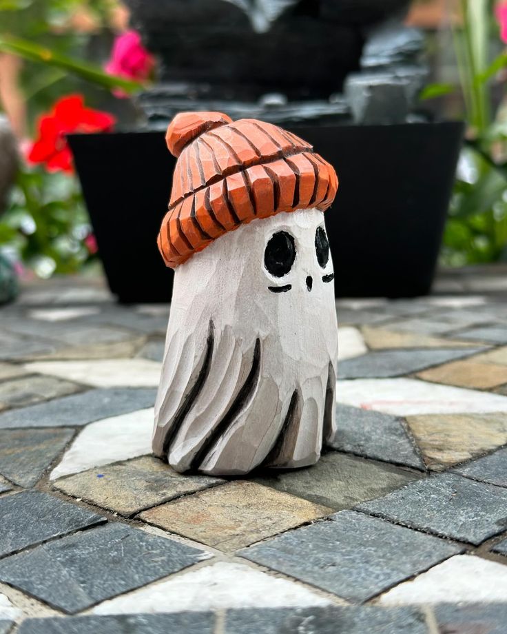 a ceramic skull with a hat on it's head sitting on a stone walkway