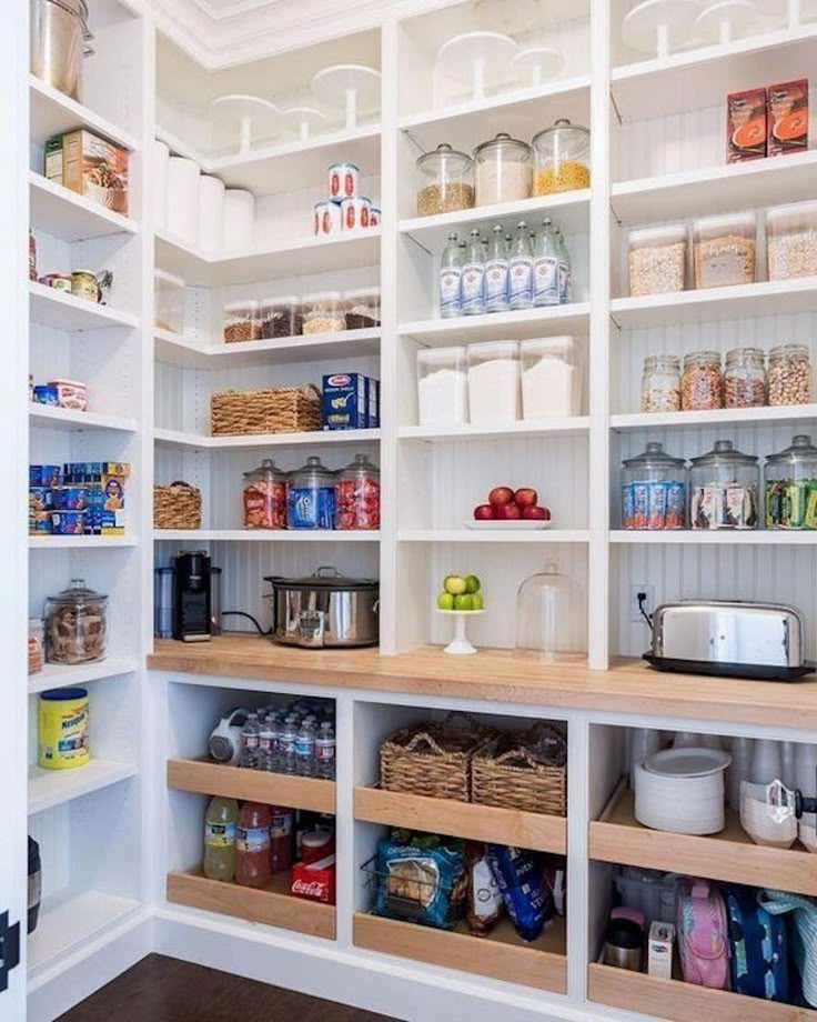 an organized pantry with white shelving and wooden shelves