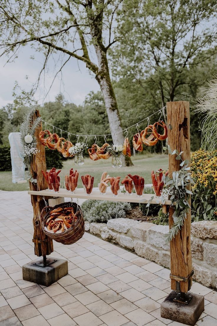 an outdoor wedding ceremony with food hanging on the line and flowers in vases at the end