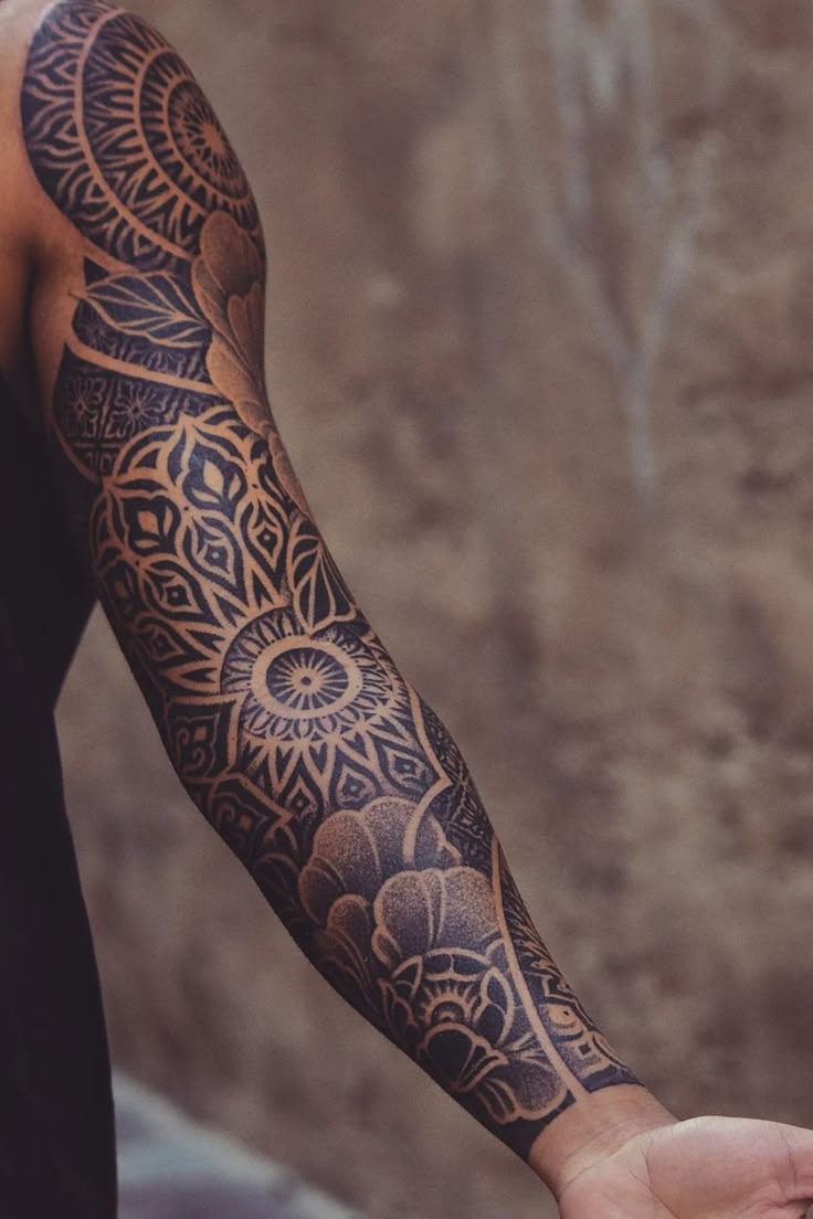 a man's arm with an intricate tattoo design on the arm and sleeve,