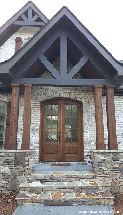 the front entrance to a house with stone and wood trimmings on it's sides