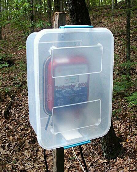 a plastic box with an electronic device in it sitting on top of a wooden post