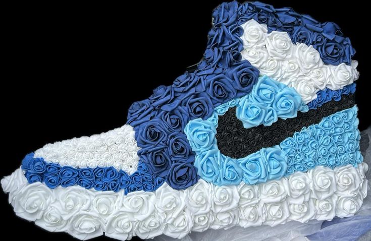 a nike shoe made out of flowers on top of a white and blue sheet cake