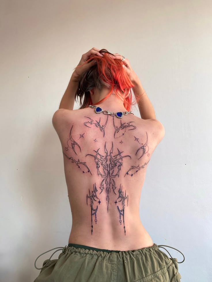 a woman with red hair and tattoos on her back