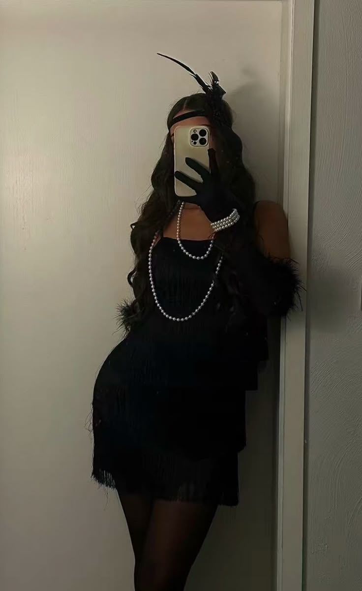 a woman taking a selfie with her cell phone wearing a black feathered dress