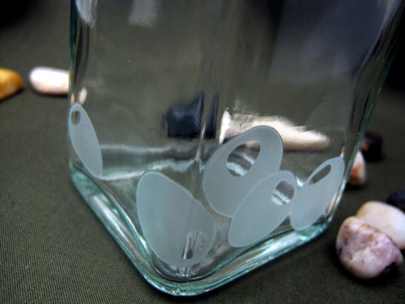 there is a glass vase with flowers in it on the table next to sea shells