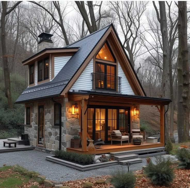 a small house in the woods with lots of windows and lights on it's roof