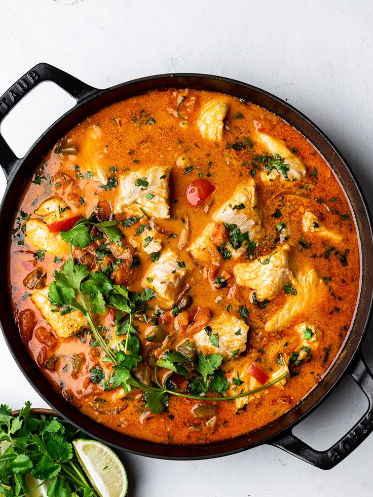 a pan filled with chicken and vegetables next to a slice of cilantro on the side