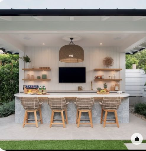 an outdoor kitchen and dining area is shown in this backyard setting with white walls, wooden chairs