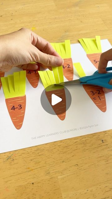 someone cutting out paper with scissors on top of a piece of paper that has been cut into carrots