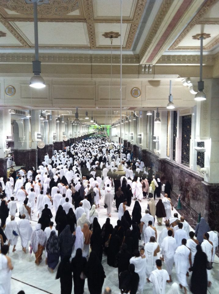 a large group of people dressed in white are walking down the hall with black and white robes