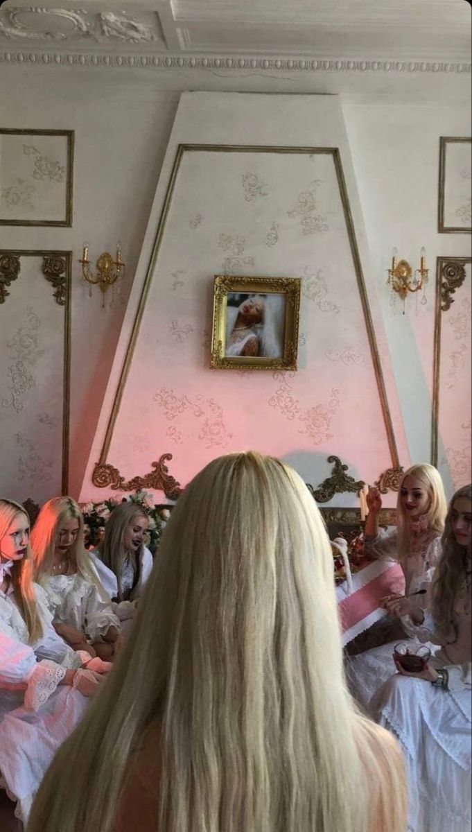 a group of women sitting in a living room next to each other with long blonde hair