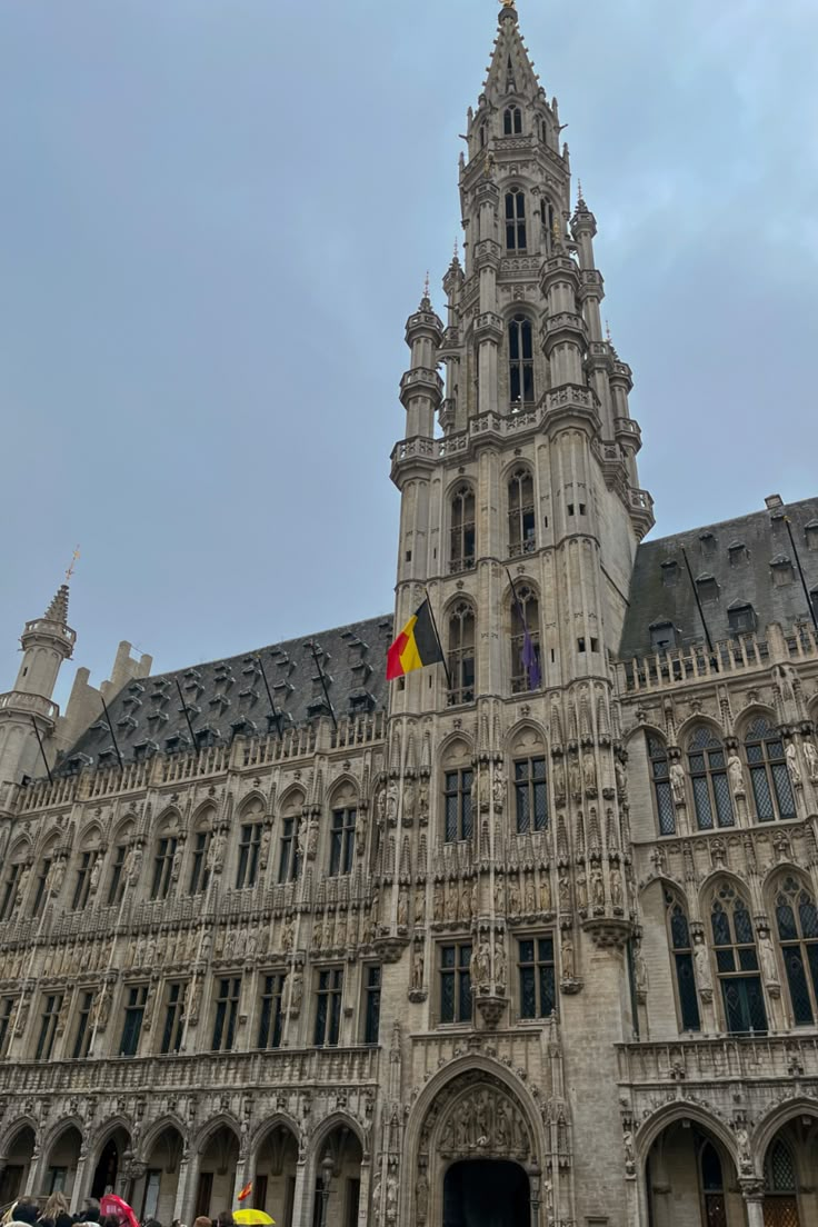 a large building with a clock tower and two flags on it's front door