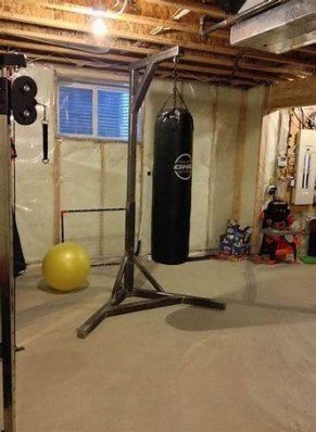 an exercise room with punching bag, gym equipment and yellow ball in the middle of it