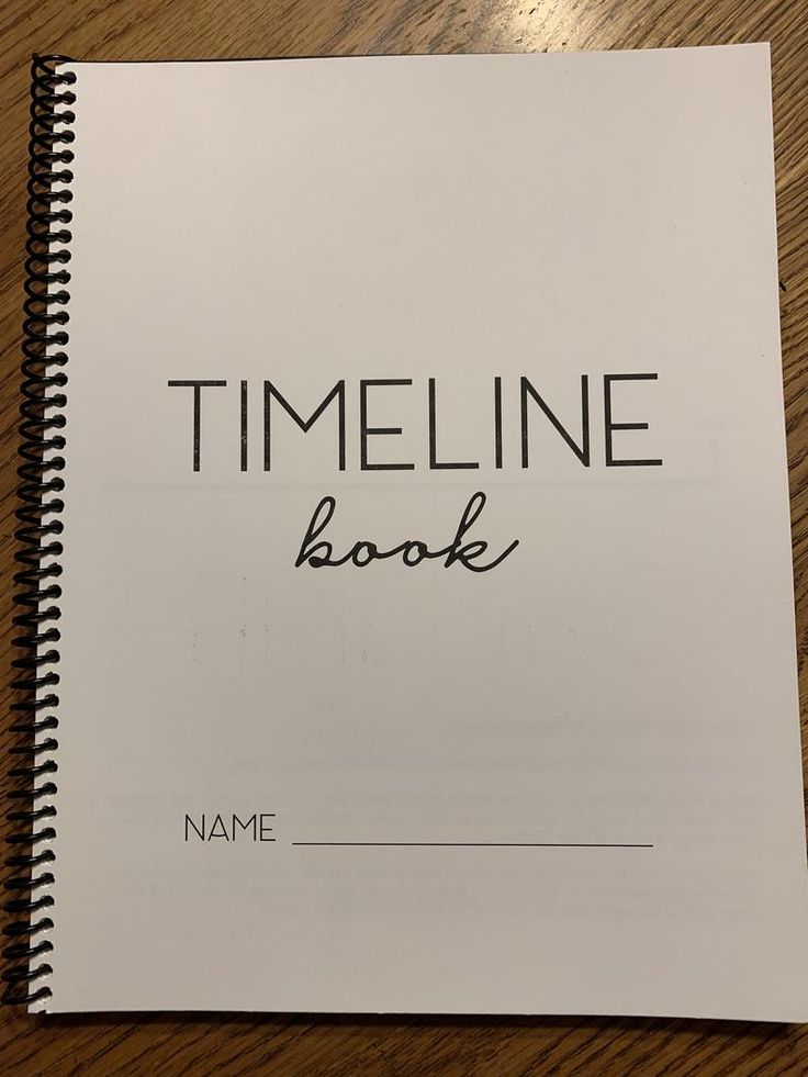 a book sitting on top of a wooden table next to a pen and paper with the word timeline