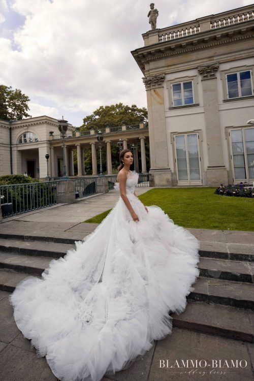 a woman in a white wedding dress standing on some steps near a large building with stairs leading up to it