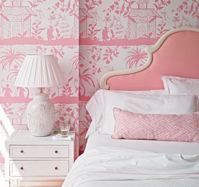 a bedroom with pink and white wallpaper and a lamp on a nightstand next to the bed