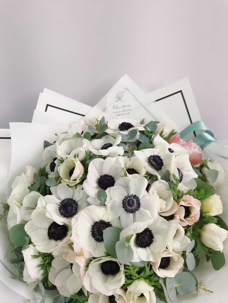 a bouquet of white and black flowers on top of some napkins next to a cup