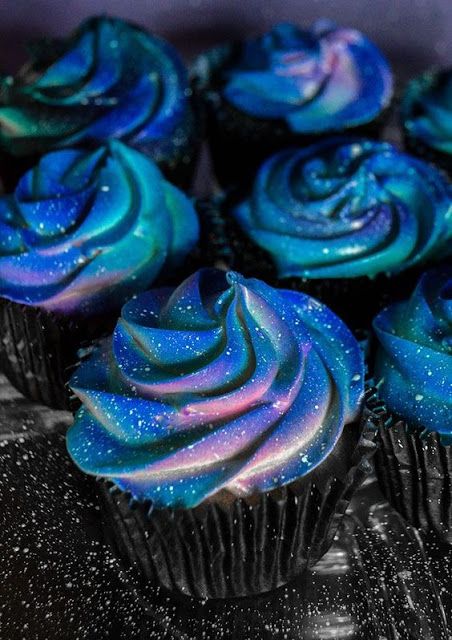 there are many cupcakes with blue frosting on the top and purple icing on the bottom