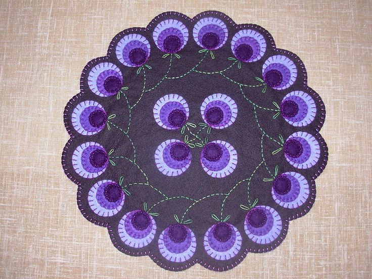 a purple doily with flowers on it sitting on top of a brown table cloth