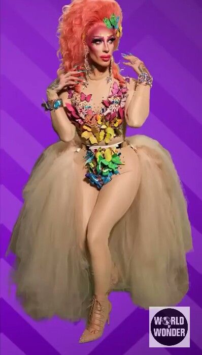 a woman dressed as a drag queen sitting on top of a purple background with her hands in her pockets