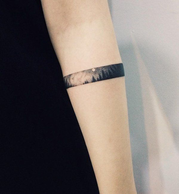 a woman's arm with a wristband tattoo that has an image of the ocean on it