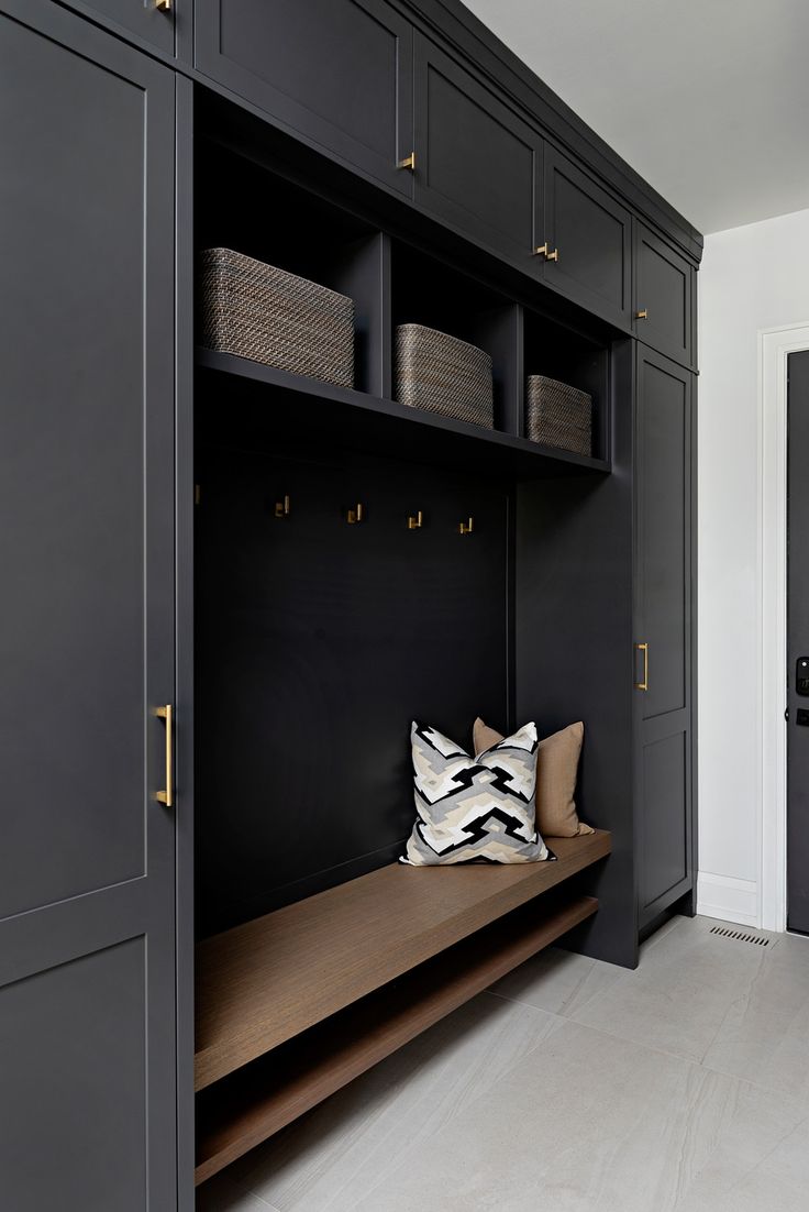 a black and white entryway with built - in bench, storage cabinets and baskets