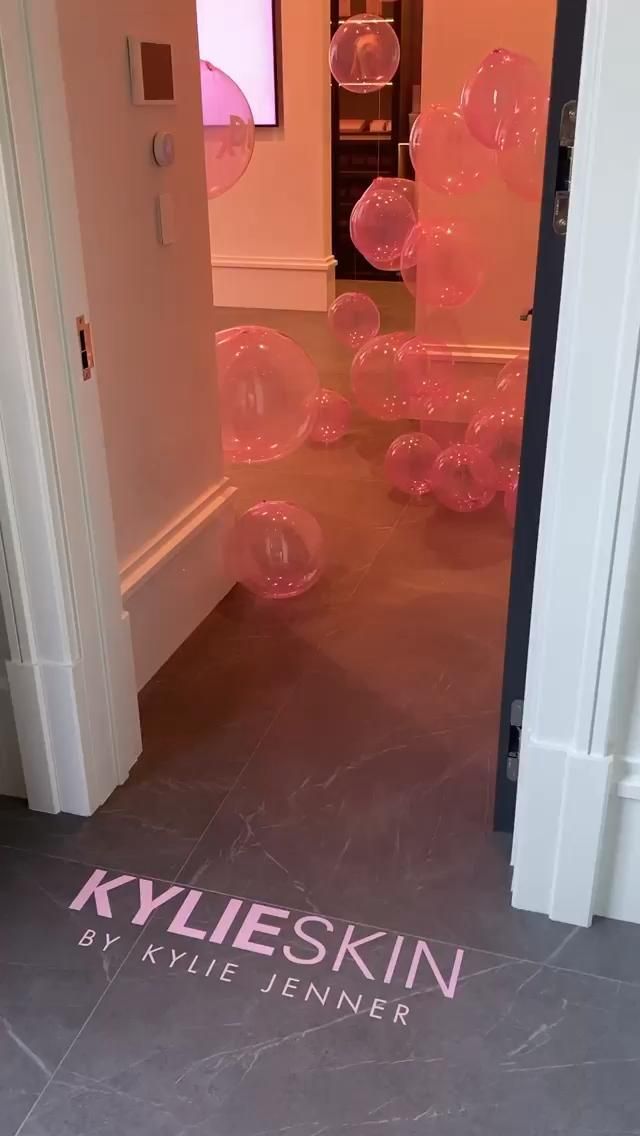 an open door with pink balloons floating in the air and on the floor next to it