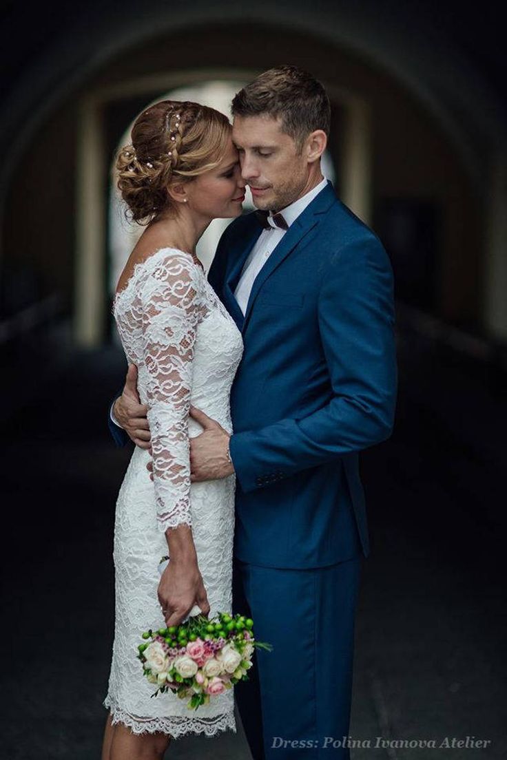 a man in a blue suit and woman in a white dress are embracing each other