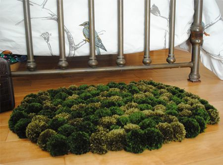 a green rug on the floor in front of a metal railing and bed with white sheets