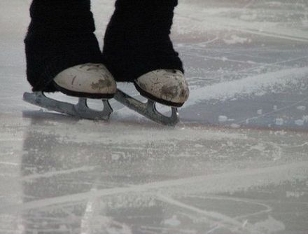 someone is standing on the ice with their feet in the air and wearing skis