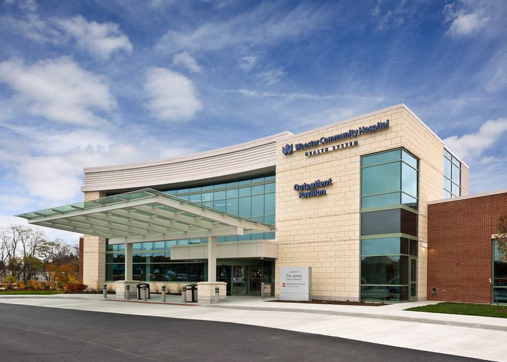 the front entrance to an office building with blue skies in the background and clouds in the sky