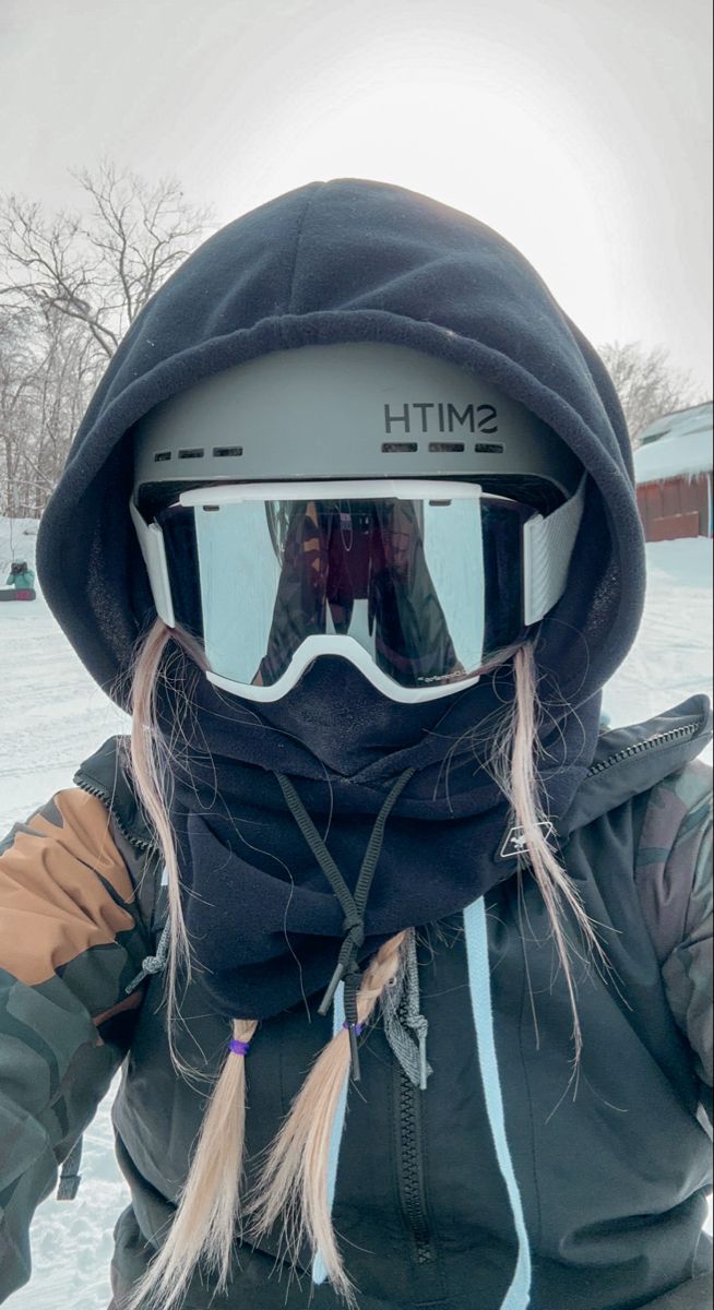 a person wearing ski goggles and a black jacket in the snow with their hair pulled back