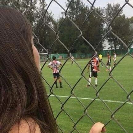 a girl is holding her hand up in front of a soccer field with other players on it