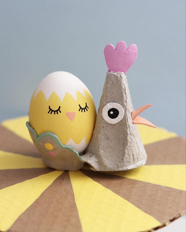 an egg shell with eyes and a bird's head on it sitting next to a rock