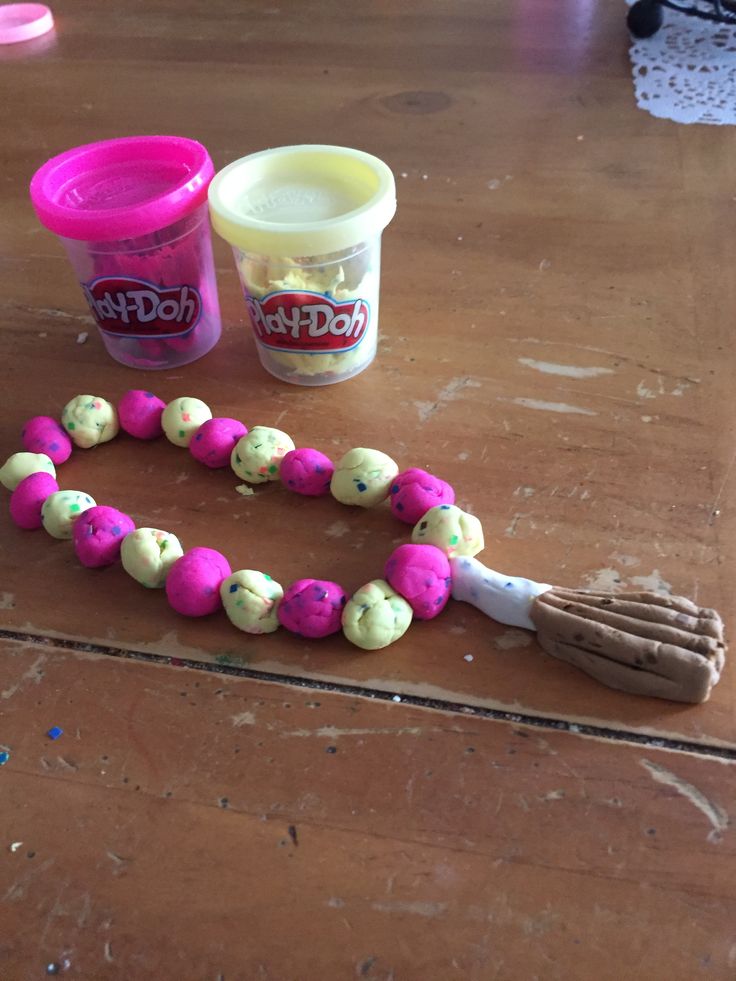 the table is covered with pink and green beads, plastic cups, and a toothbrush