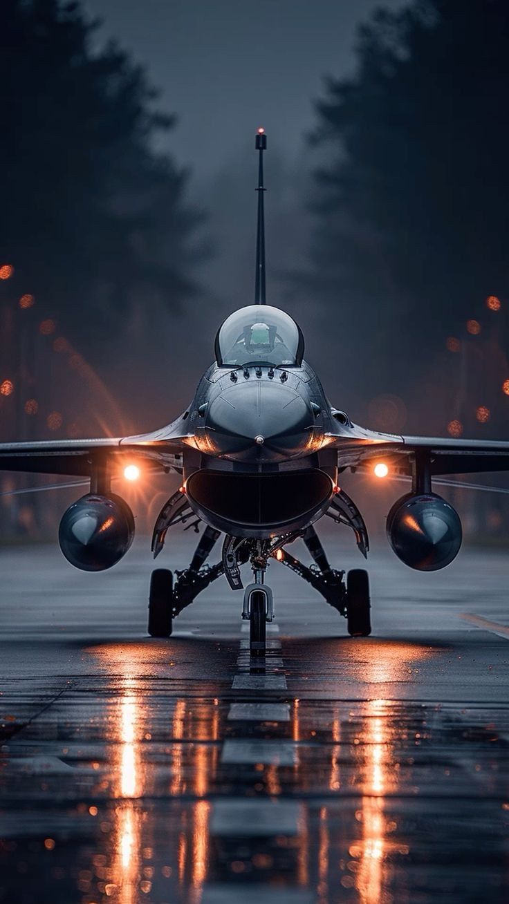 a jet airplane sitting on top of an airport tarmac at night with its lights on