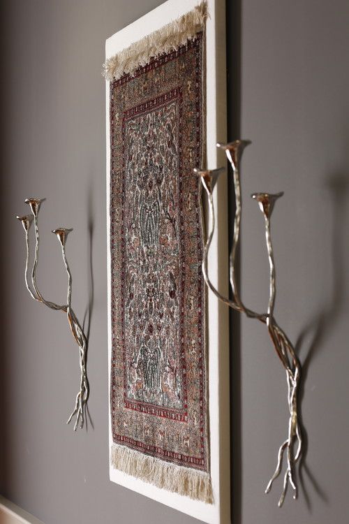 two metal candelabras are on the wall next to a rug and candlesticks