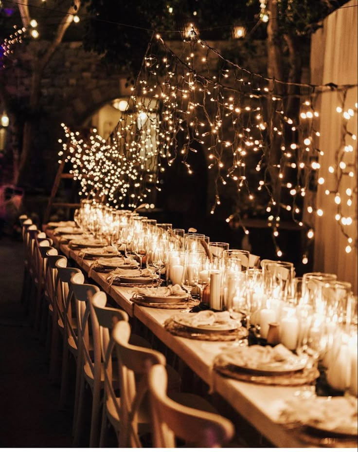 a long table is set with candles and plates for an outdoor dinner or party event