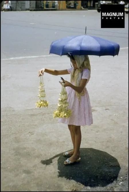 a woman in a pink dress holding an umbrella over her head with flowers on it