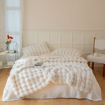 a large white bed sitting on top of a hard wood floor next to a window