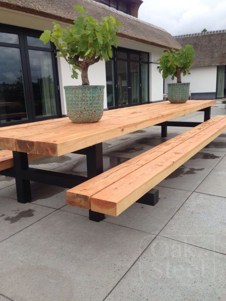 a wooden bench sitting next to a potted plant on top of a cement floor