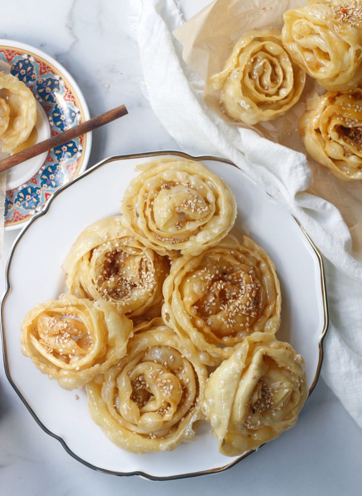 several pastries on a plate next to two plates with cinnamon rolls in the background