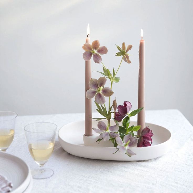 two candles are sitting on a plate with flowers