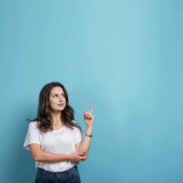 a woman is pointing at something with her finger on a blue wall and looking up