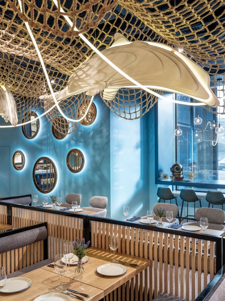 the interior of a restaurant with blue walls and wooden tables set up for two people