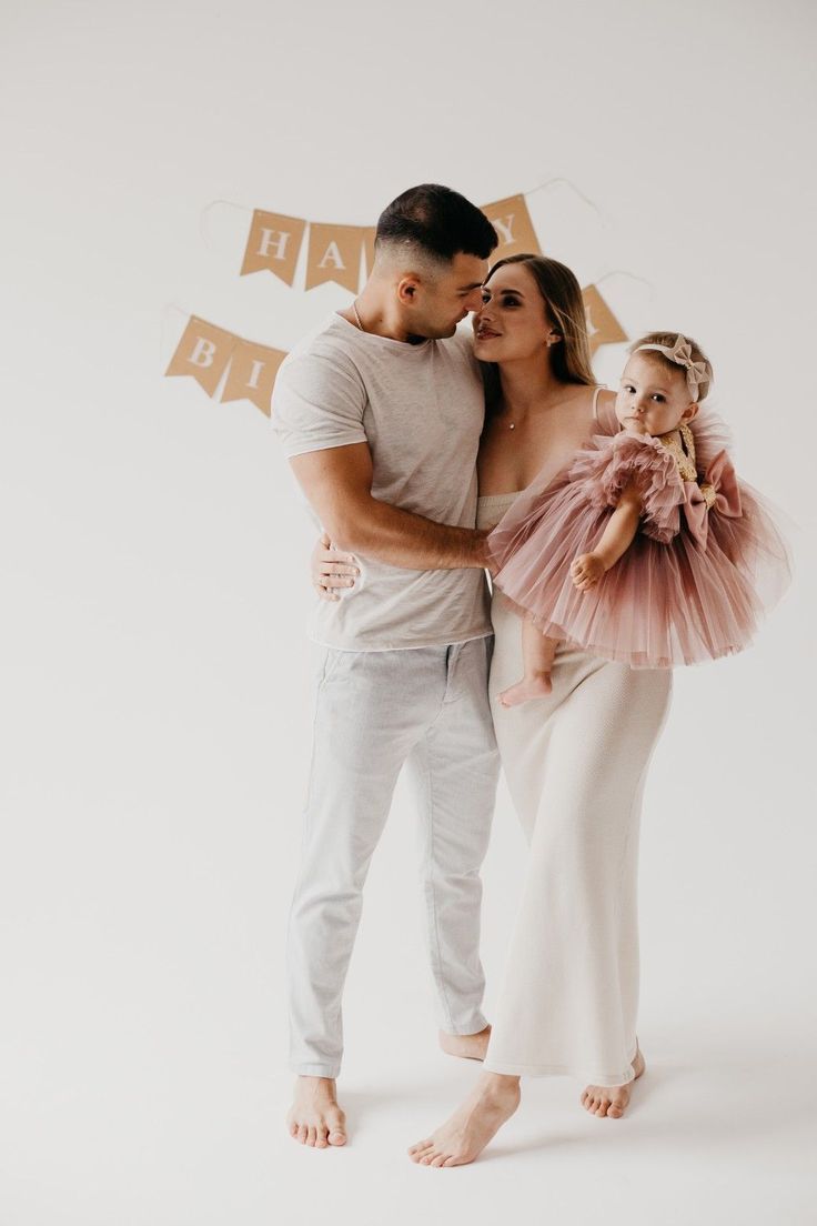 a man and woman holding a baby girl in front of a happy new year banner